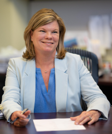 Businesswoman smiling at her desk holding a pen and paper