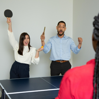 Two employees cheer during a game of ping pong in the office.