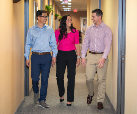 Three employees walking down a hall at an office.
