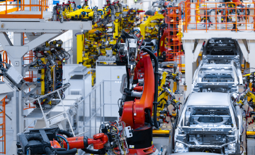 A car manufacturing plant is building cars using high tech machines and robots on an assembly line.
