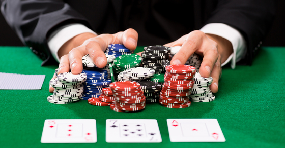 A man playing poker slides all of his chips to the center of the table.
