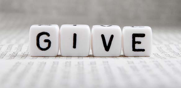 Four dice placed in a line spelling out the word "GIVE".