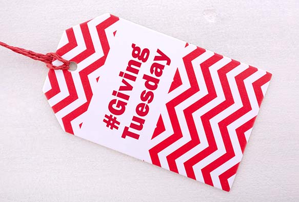 A red and white chevron tag with the text "#Giving Tuesday" against a white background.