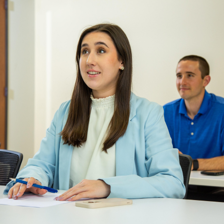 Two employees in a training sessoin looking at the front of the room 